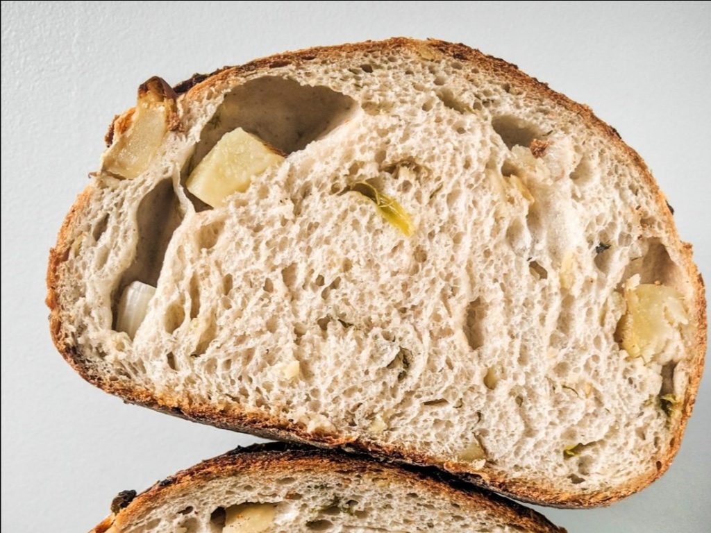 Potato dill bread from the bakehouse stacked on top of another potato dill bread.